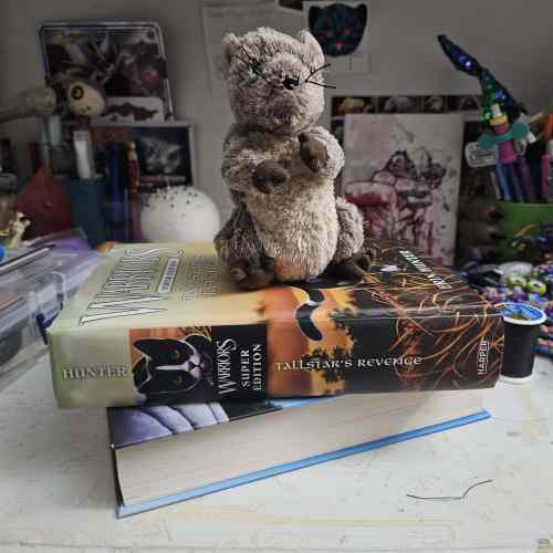 A picture of a rat stuffed animal sitting on top of a stack of two books. The one book with a visible spine is Tallstar's Revenge by Erin Hunter.