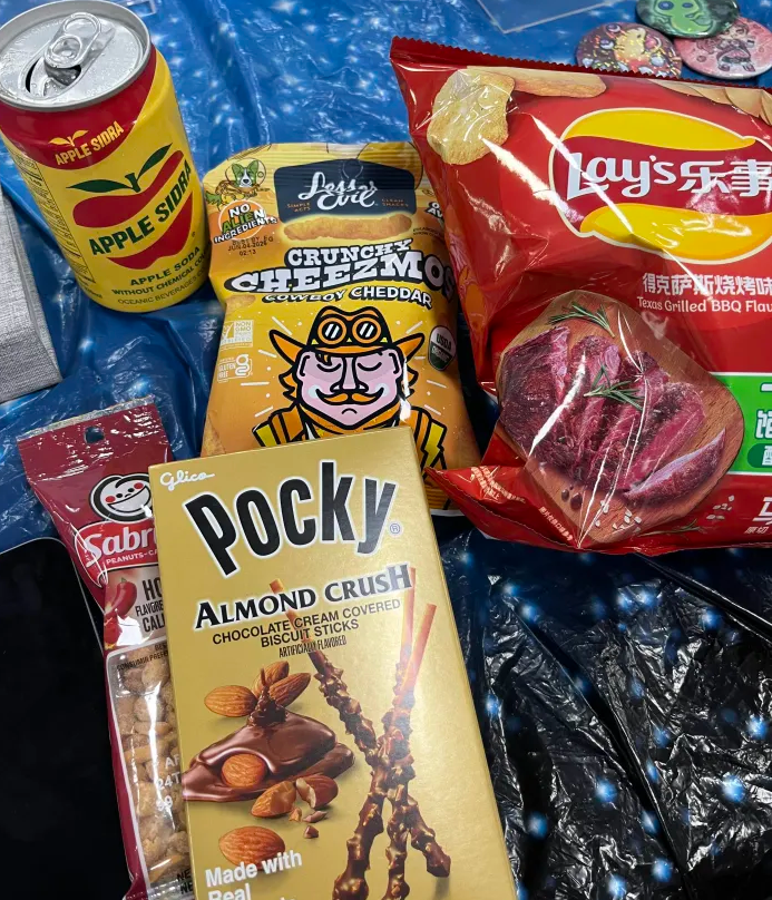 Collection of snacks; almond crunch Pocky, Lesser Evil crunchy chips, hot Sabritos peanuts, Taiwanese apple cider, and Texas barbecue-flavored Lays from Taiwan