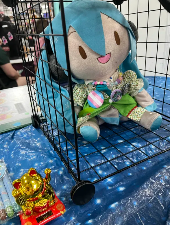 Miku plushie and a golden maneki-neko named Himawari sitting on a table with a starry cloth