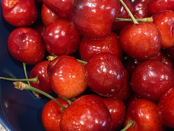 a picture of some cherries in a navy blue bowl