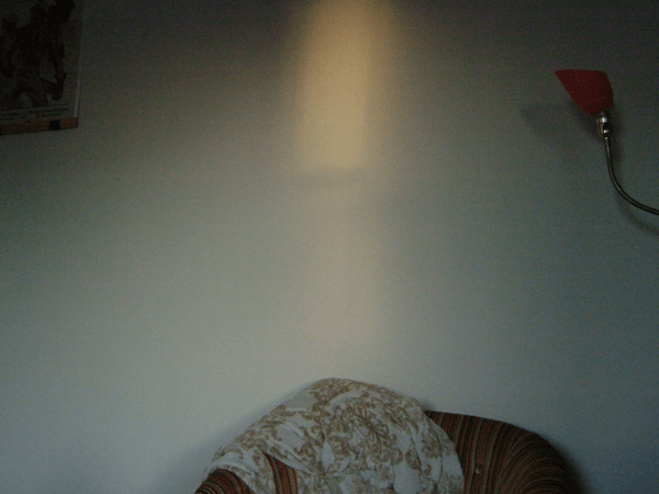 a shot of an orange-ish square of light above a living room chair that is mostly out of frame