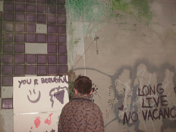 a concrete wall that has been painted on recently. a man stands in front of it looking at it