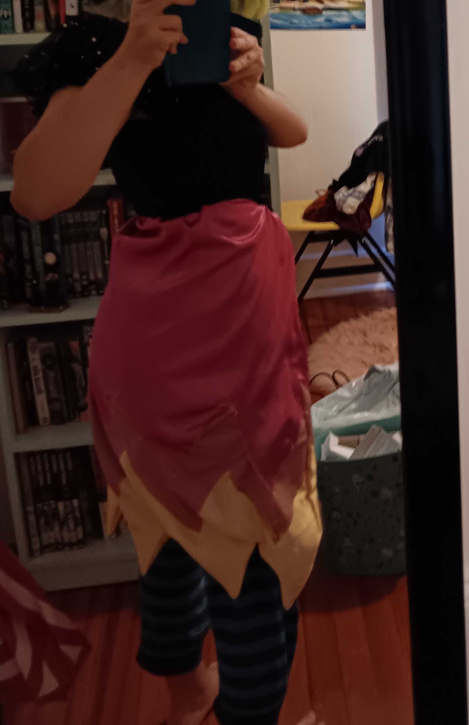 A jagged skirt goes from pink to yellow. It is sewn to a black top.