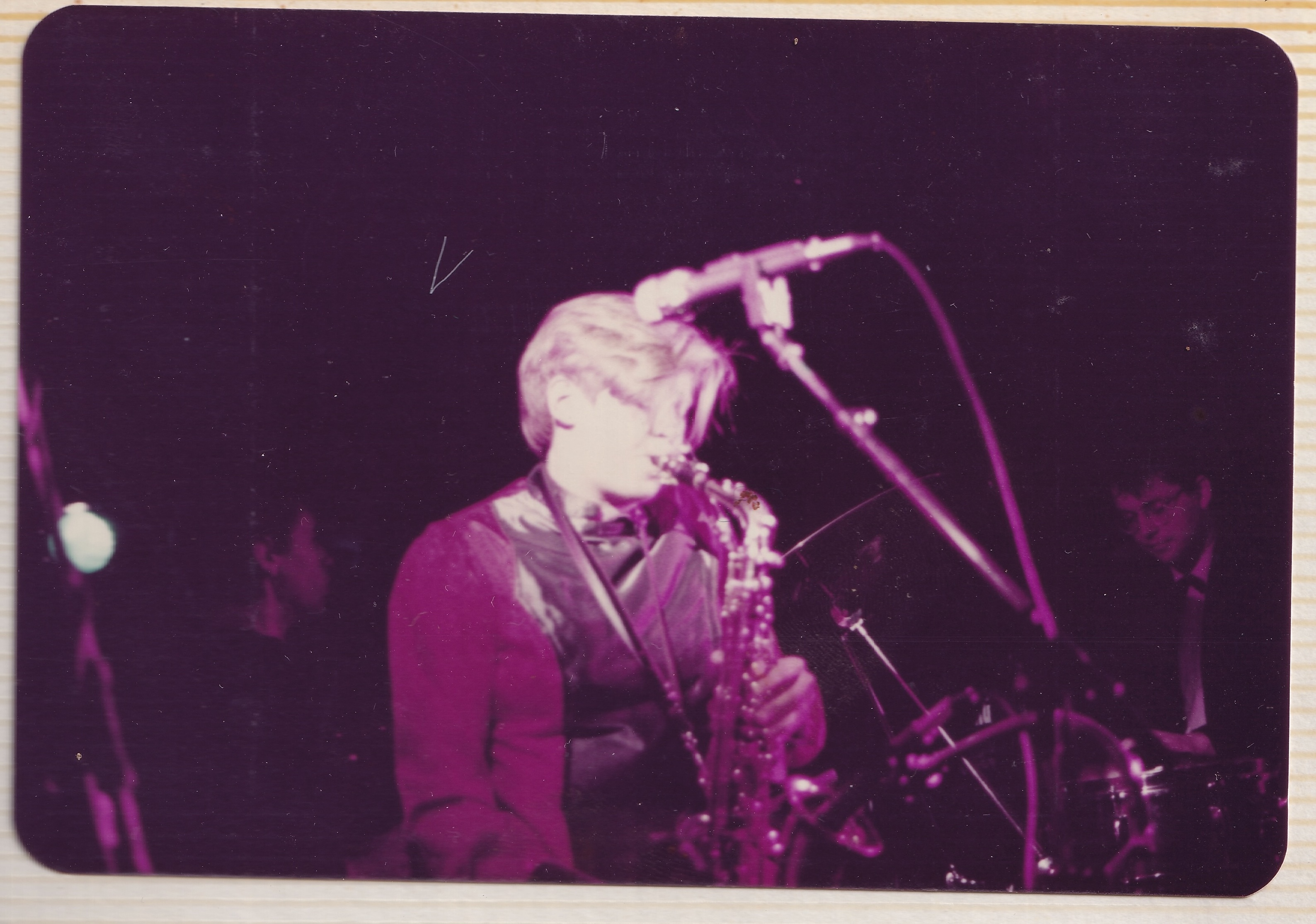 Jo playing saxophone onstage, Jon behind her
