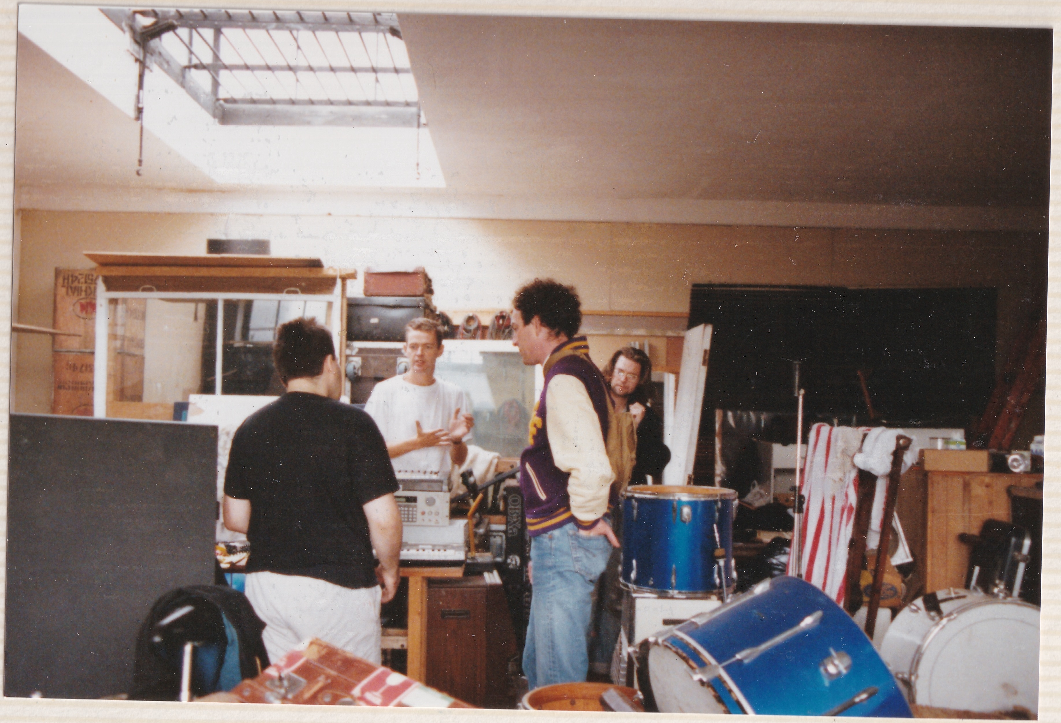 Nick and George showing Kim around a studio, Jon is scowling.