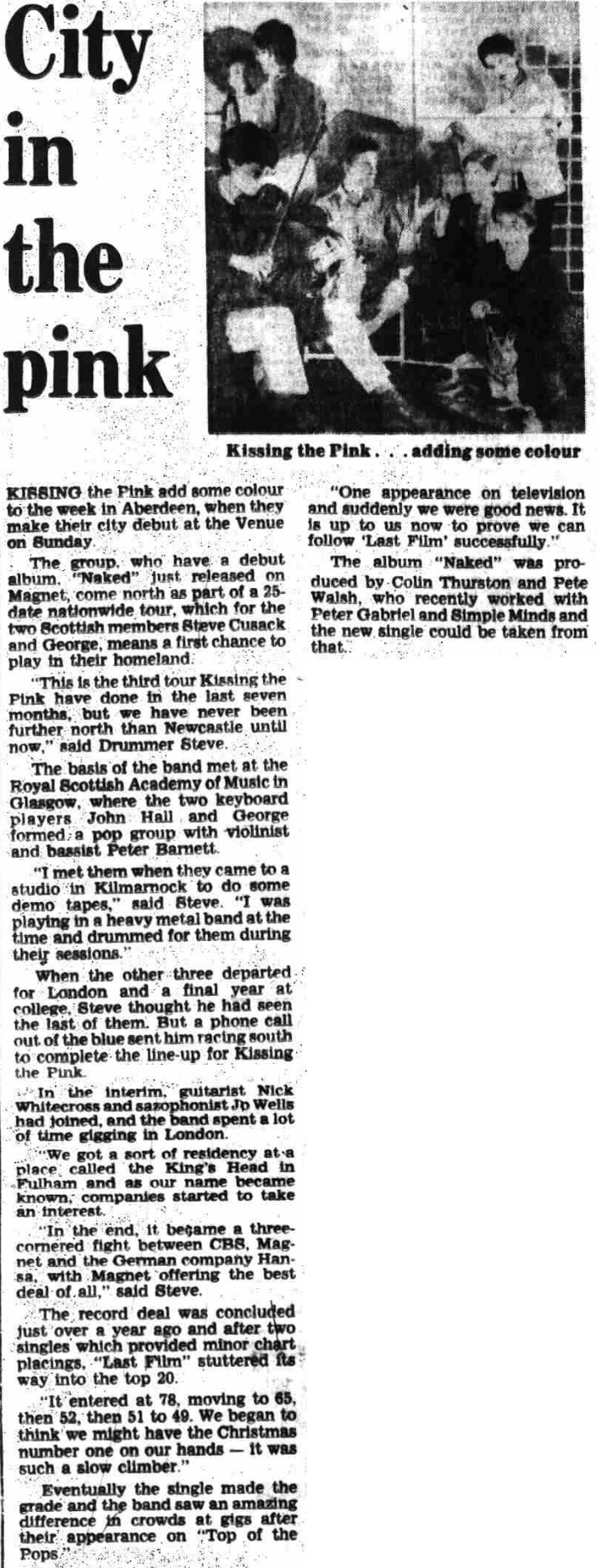 A photo of Kissing the Pink used in other articles. It consists of the 6-person Naked lineup standing in a white room. Stevie leans forward towards the camera, his arms grabbing the back of a chair. George sits in front of him on that chair, with his fist at his chin. To George's left, Nick also sits, although it's hard to tell if he's sitting on something. To George's right, Peter kneels and grabs onto the chair for stability. In front of George, Jo sits on the floor. To the left of them all, Jon is standing and looking down at the rest of them.