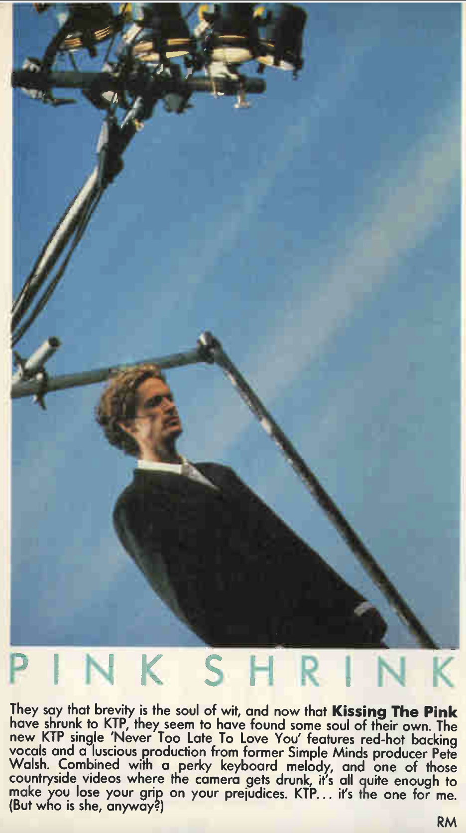 A photo of 1986 Nick Whitecross standing wearing a suit with a blue sky and a large camera light above him. Presumably from the set of the Never Too Late To Love You music video. Below him is text that is transcribed below.