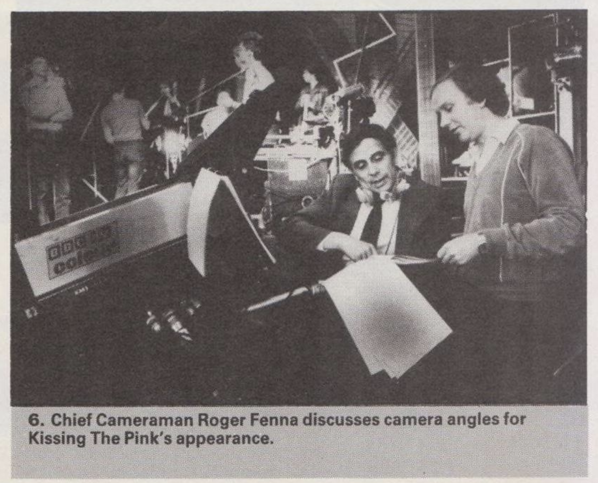 A photo of Roger Fenna talking to a producer. Behind him there is a stage where Nick, Jon, Stevie and Peter can be seen standing. Its caption is transcribed below,