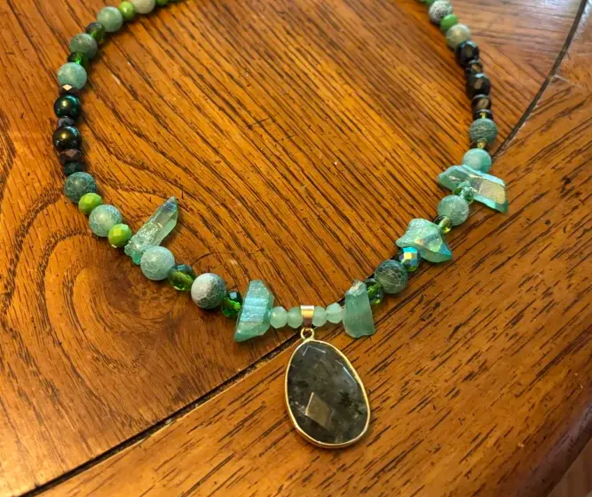 A green necklace with crystal beads and a dark green pendant