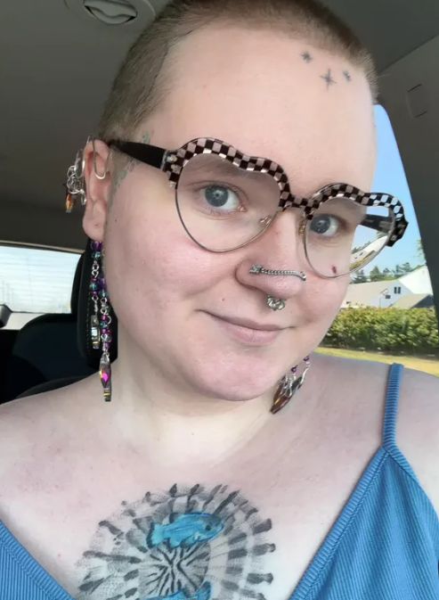 A bust shot of me, a white feminine individual with short light hair and heart shaped glasses