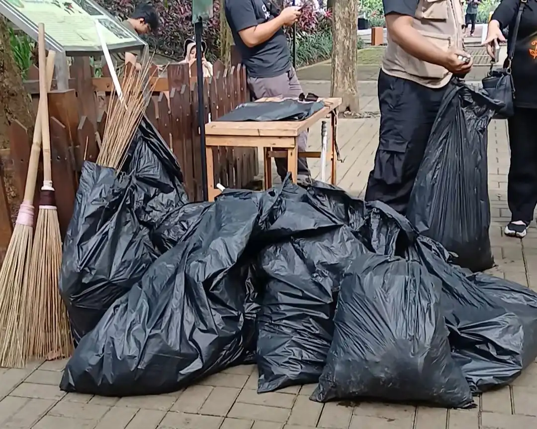 Tumpukan kantong sampah hitam hasil plogging di area taman