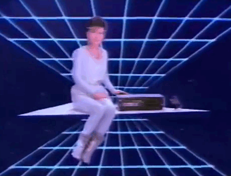 a groovy 80s lady talking about vcrs in front of a blue grid