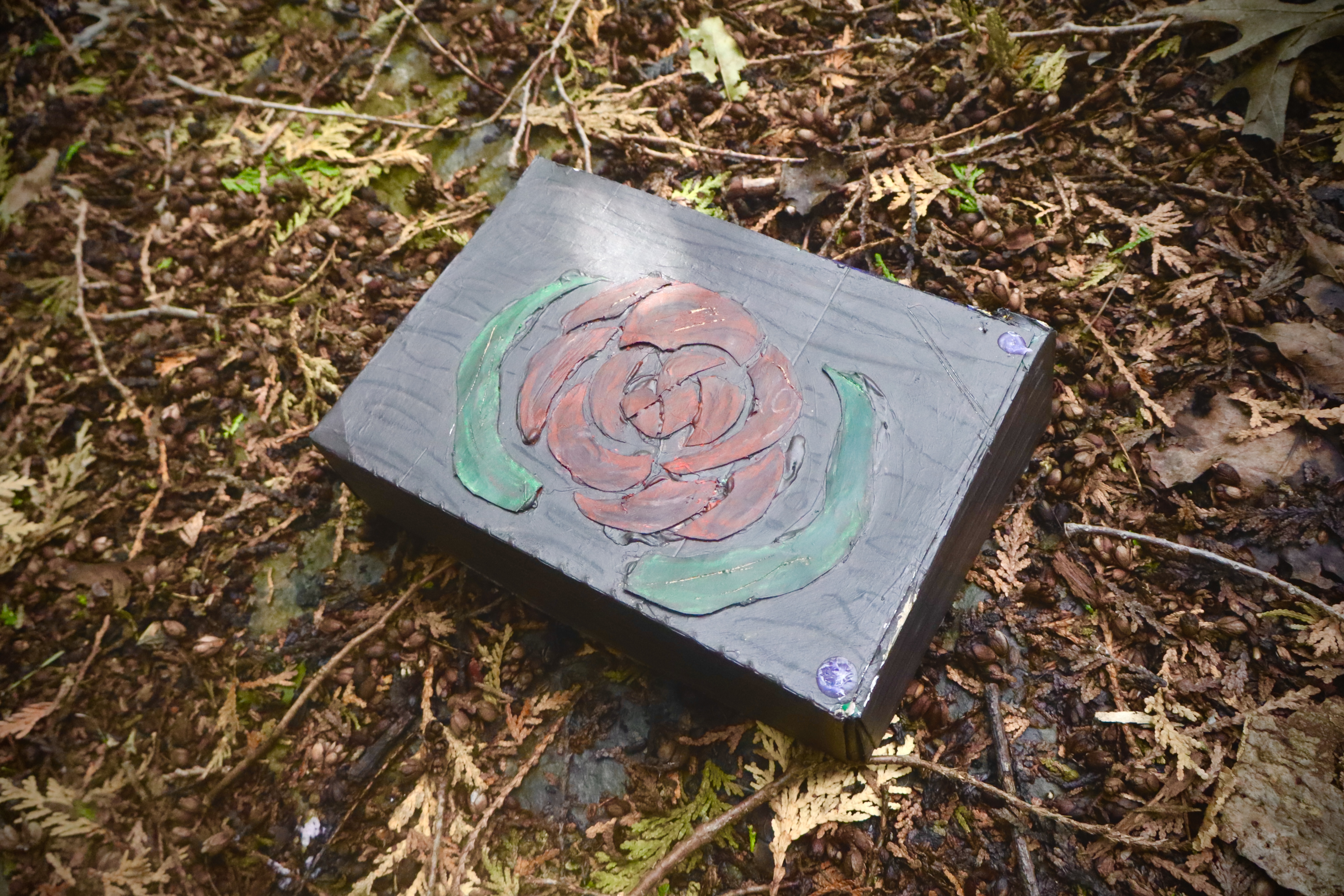 An old wooden box, with a red rose carved into it and painted