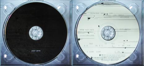 an image showing two cds side by side. The left disc is black with the text Year Zero and the right disc is white covered in strings of binary code.