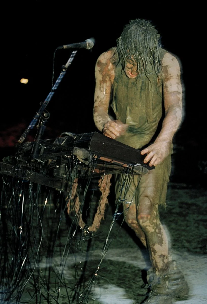 image of trent reznor covered in mud playing the keyboard at woodstock 94