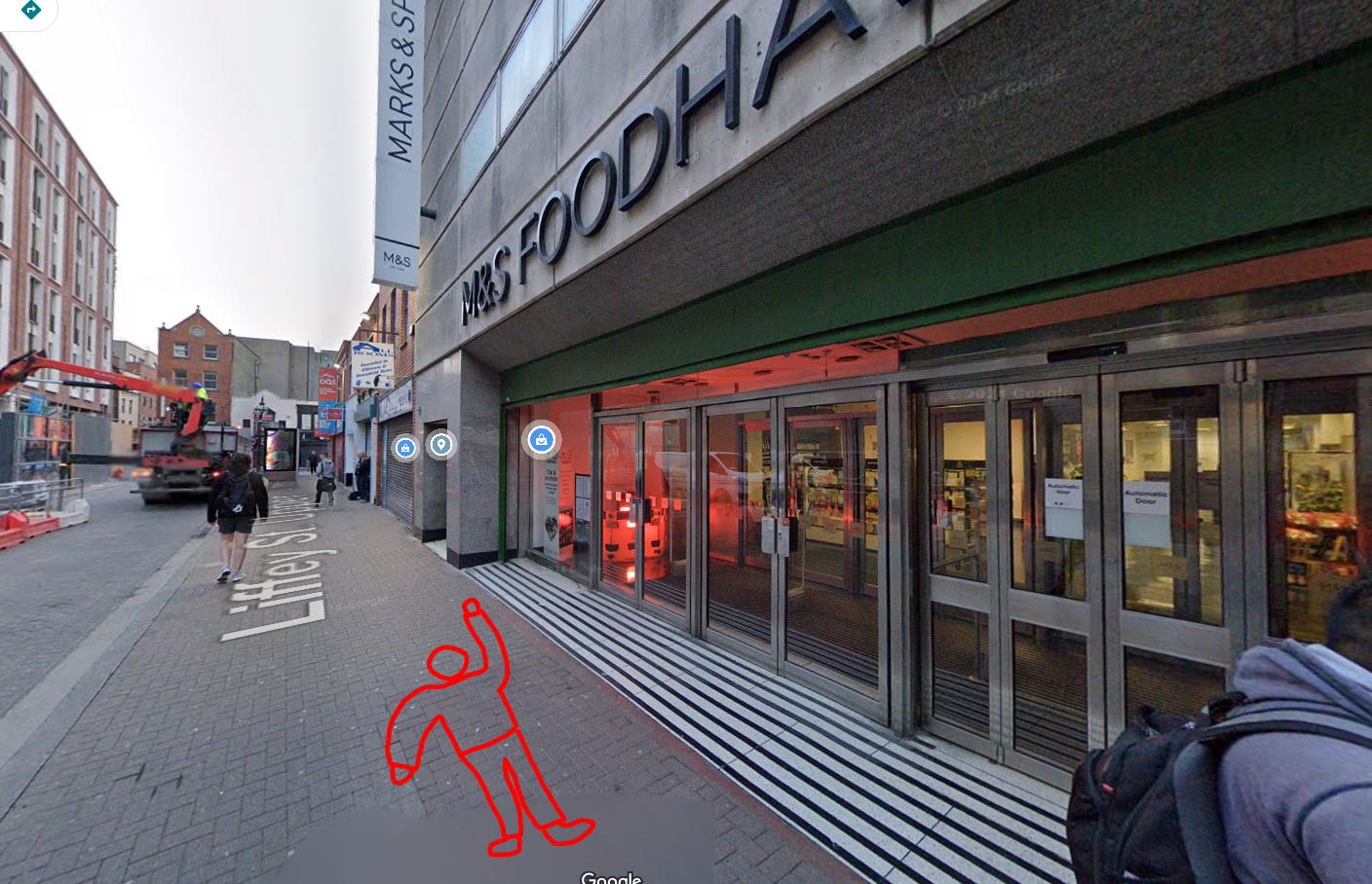 a poorly drawn red stick figure is laying face down in front of the m&s food hall on liffey street in dublin, ireland