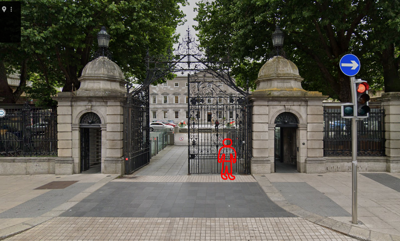 the poorly drawn red stick figure stands outside the gates of leinster house, the building that serves as the meeting place of irish parliament