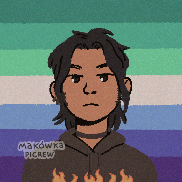 man with shaggy hair and a hoodie with flames on the chest standing in front of gay pride flag