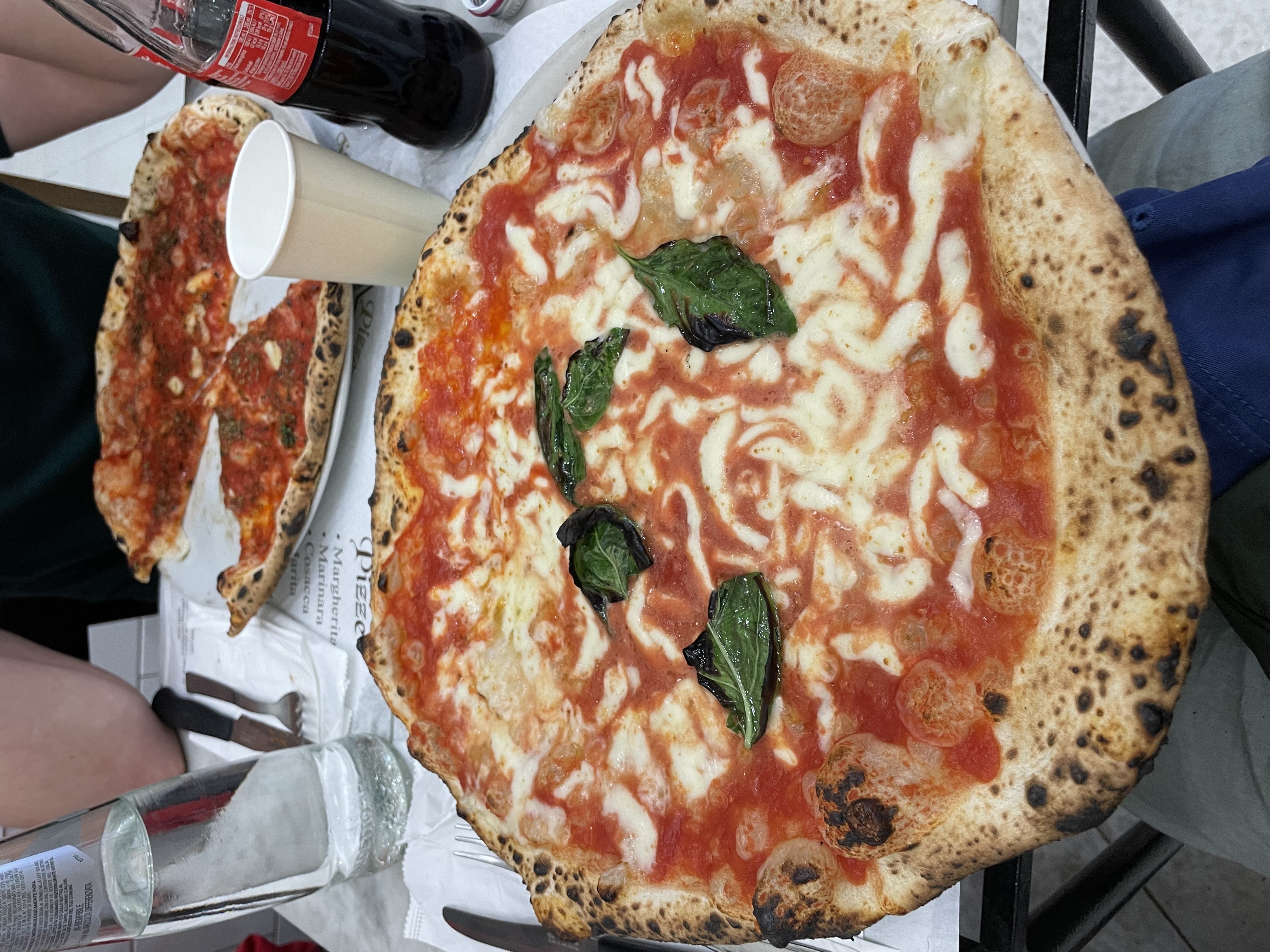 Margherita and marinara pizzas on a table.
