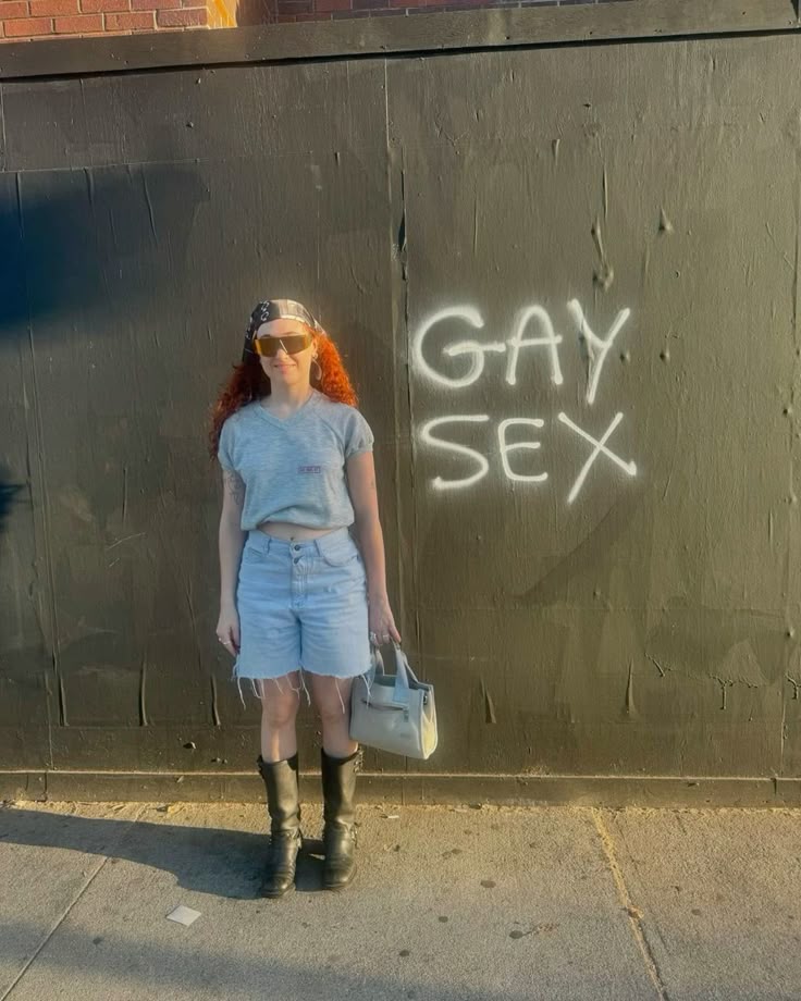 chappell roan standing next to graffiti that says gay sex