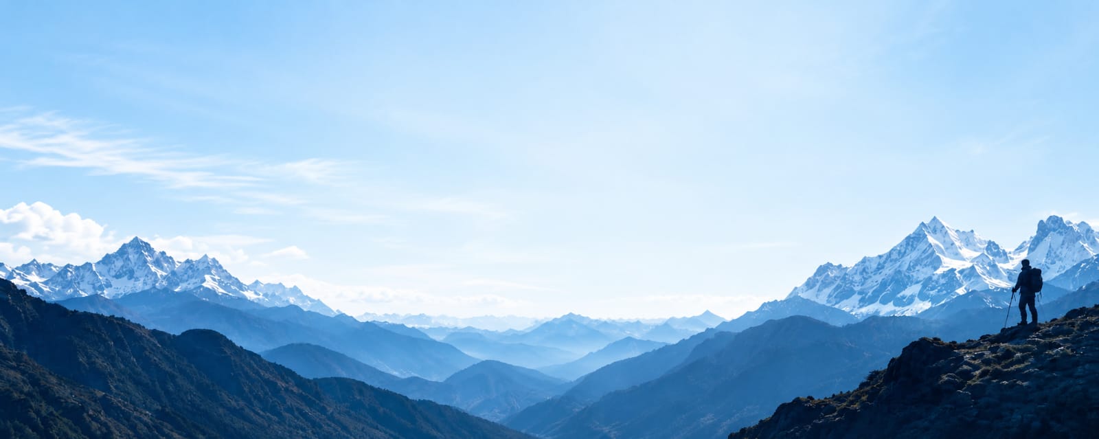 A trekker overlooking the blue Himalayan valleys and snow-covered peaks